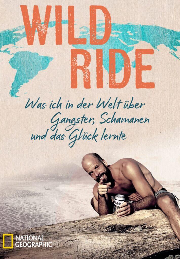 Buchcover von Wild Ride: Andreas Brendt am Strand mit einer Weltkarte im Hintergrund